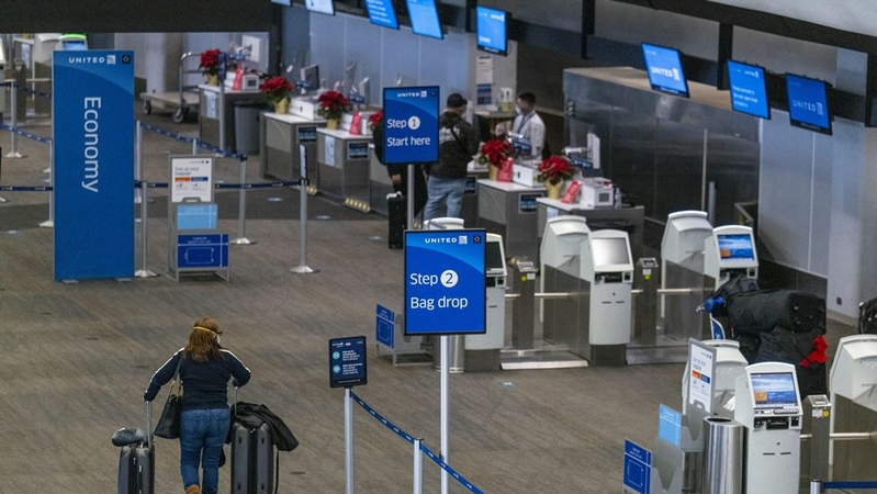 A traveler wearing a protective mask walks with luggage to the United Airlines check-in counter at San Francisco International Airport in San Francisco, on Dec. 21, 2020. MUST CREDIT: Bloomberg photo by David Paul Morris.