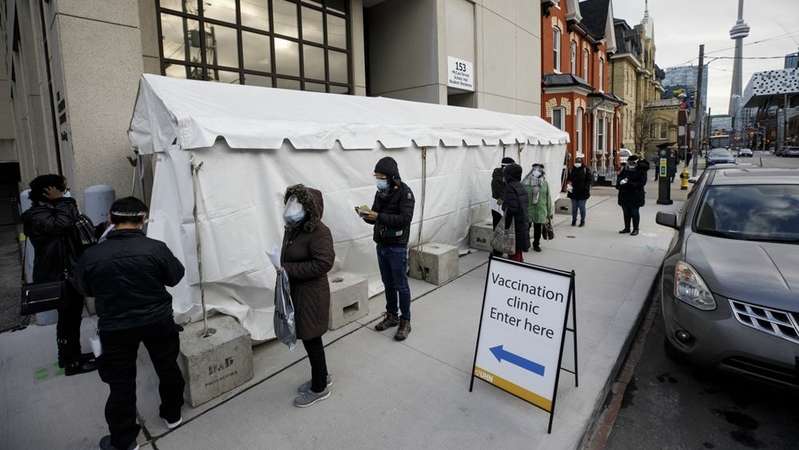 Healthcare workers wait in line outside a Toronto vaccination clinic on Dec. 15, 2020. MUST CREDIT: Bloomberg photo by Cole Burston.
