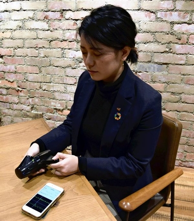 A Nissin Foods Holdings Co. employee uses a device that measures stress levels in two minutes. (The Yomiuri Shimbun)