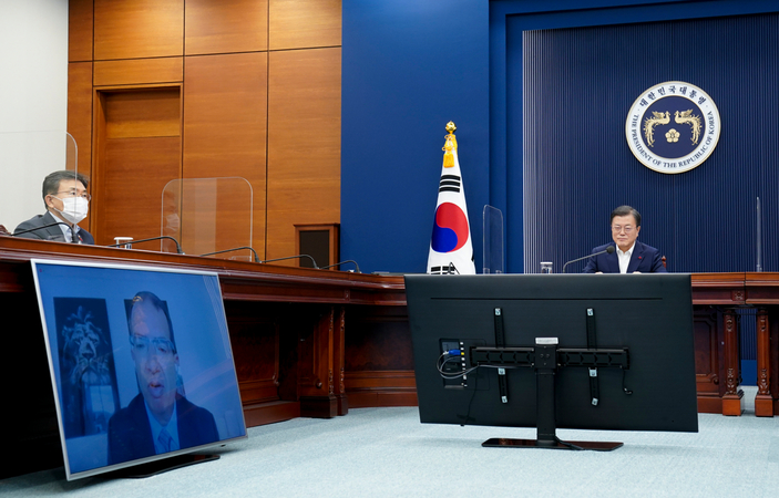 President Moon Jae-in (R) talks with Moderna CEO Stephane Bancel (on the monitor) via video conference at the presidential office in Seoul on Monday. (Presidential office)