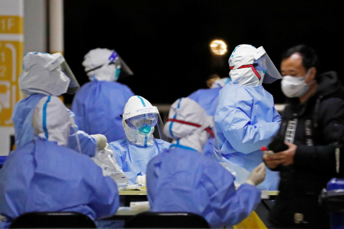 Workers in protective suits are seen at a makeshift nucleic acid testing site inside a parking lot of Shanghai Pudong International Airport, after new cases of COVID-19 in Shanghai, on Nov 22, 2020. [Photo/Agencies]