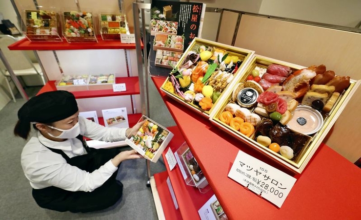 A sales assistant shows a sample of an osechi set of traditional New Year’s delicacies at the Matsuya Ginza department store in Chuo Ward, Tokyo, on Dec. 18. Almost all sets have been sold out. (The Yomiuri Shimbun)