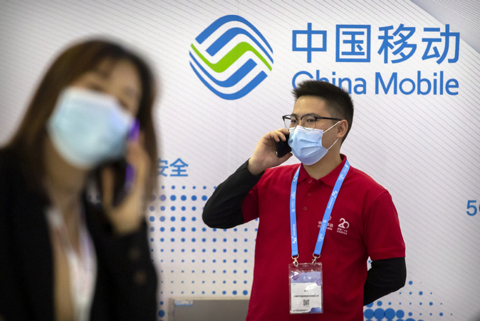 People talk on their cellphones at the booth of China Mobile during an expo in Beijing. [Photo/Agencies]