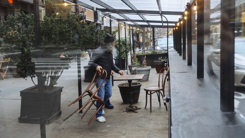 A worker removes chairs from the outdoor dining tent of a restaurant in New York. Photographer: Angus Mordant/Bloomberg