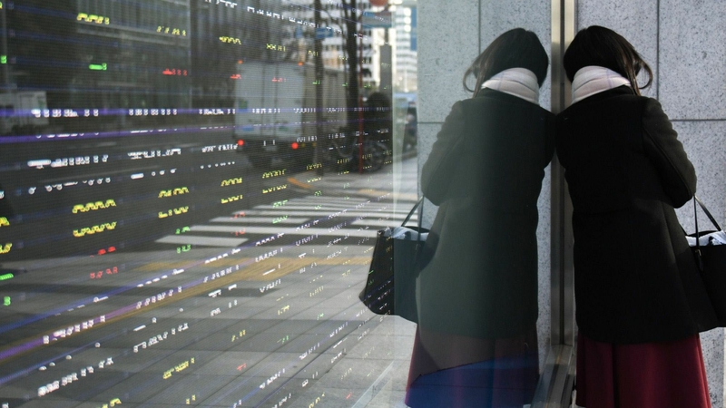A pedestrian stands against an electronic stock board outside a securities firm in Tokyo on Jan. 4, 2021. MUST CREDIT: Bloomberg photo by Noriko Hayashi.