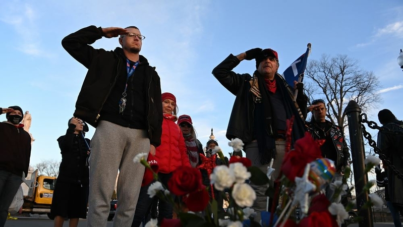 Tony Naples, left, and Gary Phaneuf salute at a memorial for Ashli Babbitt on Jan. 7, 2021, in Washington. Babbitt was shot and killed during the riot at the Capitol the day prior. MUST CREDIT: Washington Post photo by Matt McClain