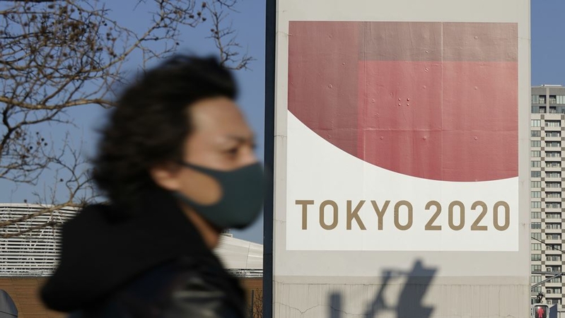 A pedestrian wearing a protective mask walks past an advertisement for the now-postponed Tokyo 2020 Olympic Games in Tokyo on Jan. 14, 2021. MUST CREDIT: Bloomberg photo by Toru Hanai.