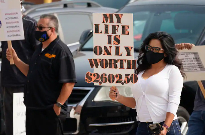 Jimena Peterson waves a sign during a protest outside the offices of the Occupational Safety and Health Administration in downtown Denver in September.
The protest was staged by the union representing employees at a Colorado meatpacking plant where six workers died of covid-19 and hundreds more were
infected this past spring. (David Zalubowski/ AP)