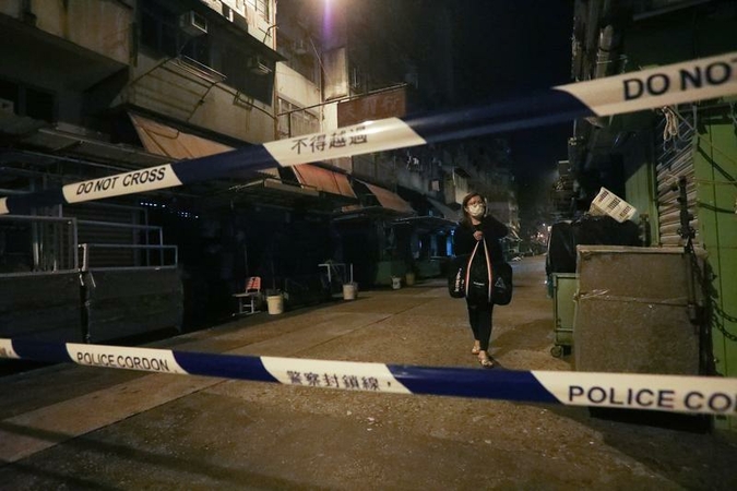 A woman stops in front of a police cordon line surrounding a lockdown area in Kowloon, Hong Kong, Jan 23, 2021. (CALVIN NG/CHINA DAILY)