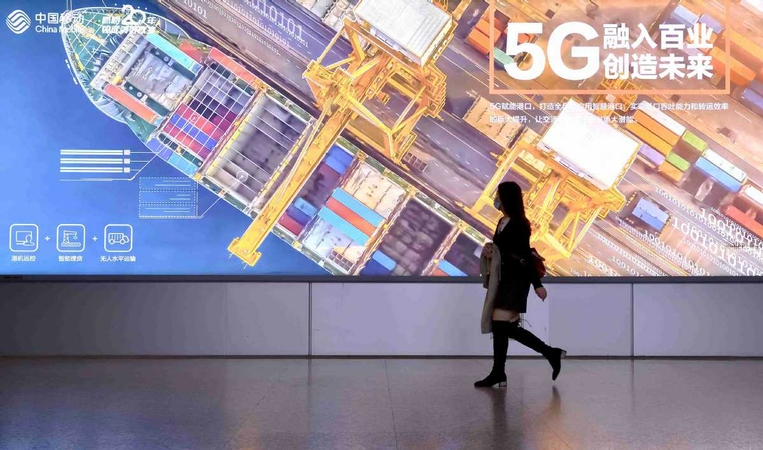 A pedestrian passes a display promoting China Mobile's 5G services in Guangzhou, Guangdong province, in November. CHEN YIHANG/FOR CHINA DAILY