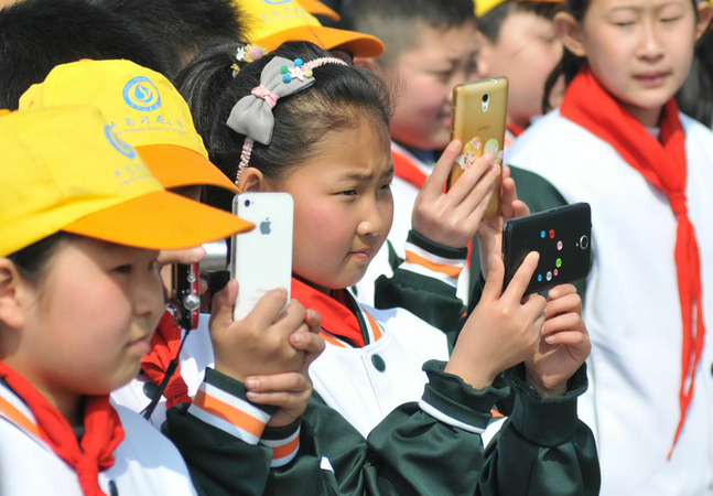 Primary school students take photos of sailboats during an outdoor course in Qingdao, Shandong province, in March, 2018. [Photo by Wang Haibin/For China Daily]
