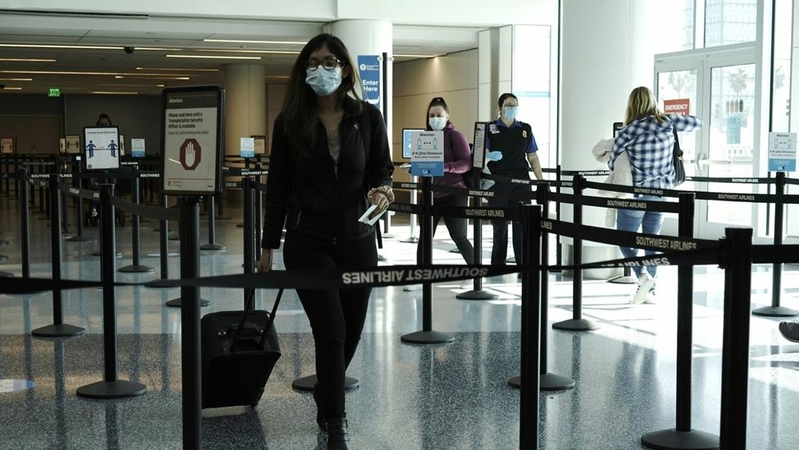 Travelers wearing protective masks walk through Los Angeles International Airport in Los Angeles on Nov. 22, 2020. MUST CREDIT: Bloomberg photo by Bing Guan.