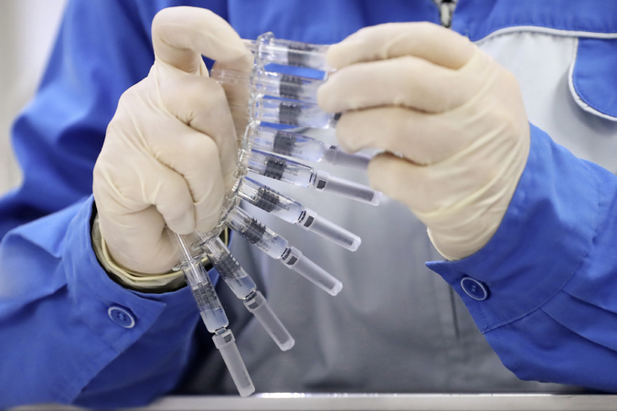 A staff member checks tags on prefilled syringes of inactivated COVID-19 vaccine at packing line of Sinovac Life Sciences Co., Ltd. in Beijing, March 23, 2020. [Photo/Xinhua]
