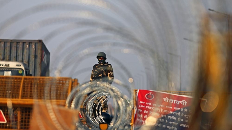 A police officer in riot gear stands guard beyond razor wire coils along a highway in Ghazipur on the outskirts of New Delhi, India, on Feb. 6, 2021. MUST CREDIT: Bloomberg photo by Anindito Mukherjee