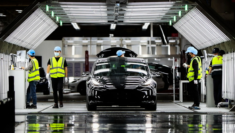 Employees put finishing touches to a vehicle at Tesla's gigafactory in Shanghai on Nov 20. [Photo/Xinhua]