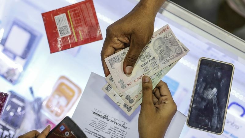 A customer pays Indian Rupee banknotes to a vendor at a sim card store in Mumbai on April 21, 2018. MUST CREDIT: Bloomberg photo by Dhiraj Singh.