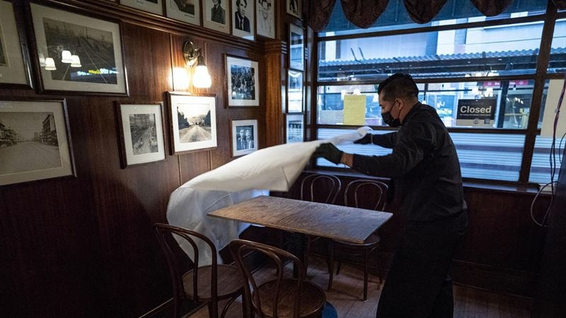 A worker puts down a table cloth at a restaurant in San Francisco on March 9, 2021. MUST CREDIT: Bloomberg photo by David Paul Morris.