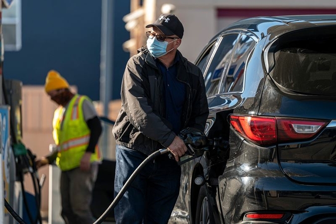 A person wearing a protective mask holds a fuel pump nozzle at a Chevron gas station in San Francisco on March 11, 2021. MUST CREDIT: Bloomberg photo by David Paul Morris.