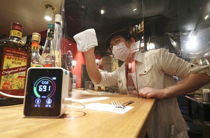 A CO2 sensor, left, and a tall plexiglass partition are set up at a bar in Shibuya Ward, Tokyo, on Thursday. (The Yomiuri Shimbun)
