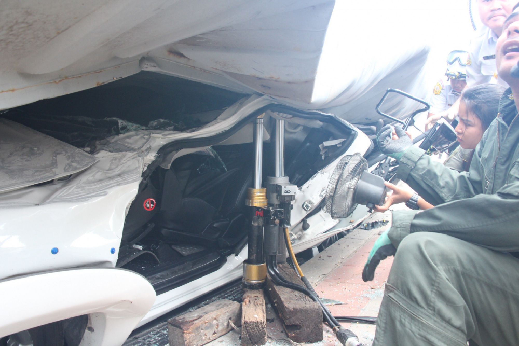 Driver cut free after truck carrying soybeans tips over on to his car