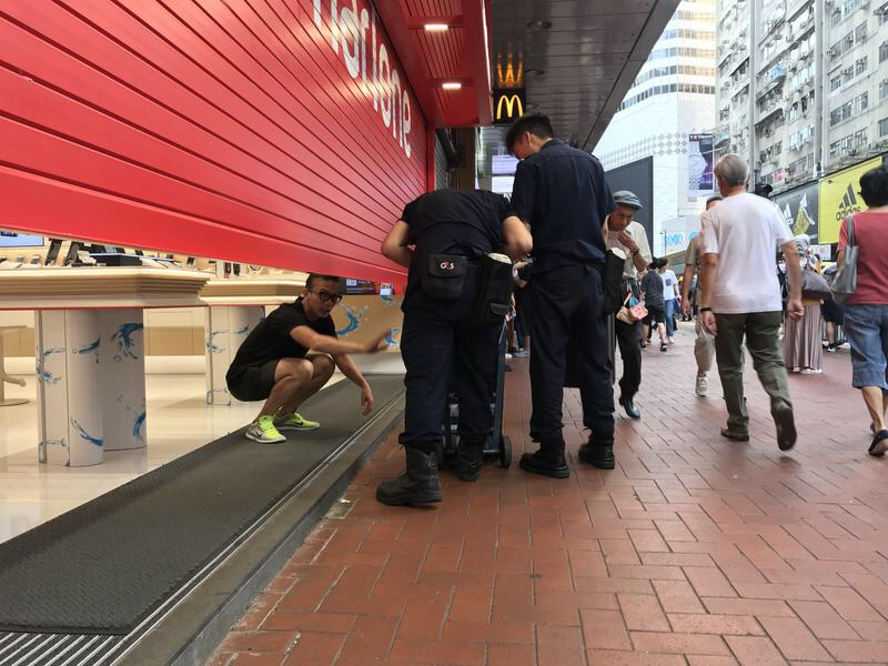 A Vodafone Smart staff pulls down a shutter while protests is taking place in Causeway Bay, Hong Kong, on July 28, 2019. (PHOTO / CHINA DAILY