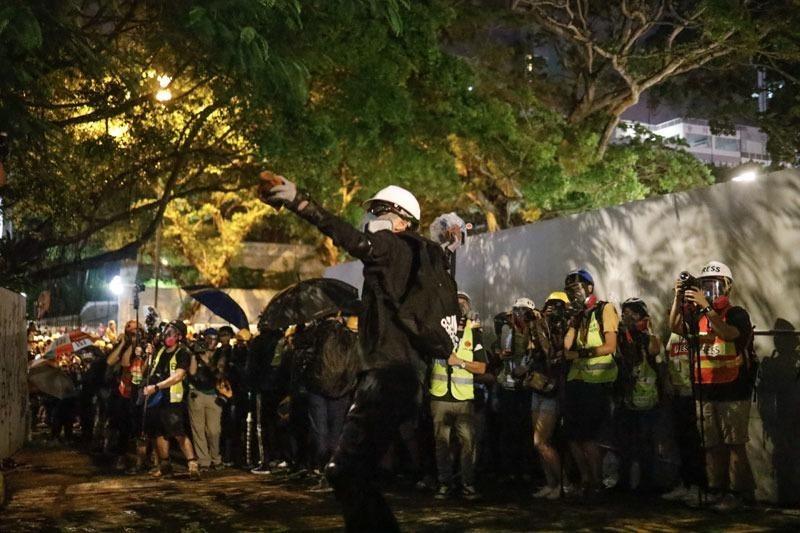 A protester hurls a brick into the Tsim Sha Tsui police station, Hong Kong, Aug 3, 2019. (PHOTO / CHINA DAILY)