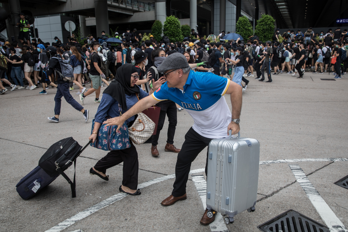 HONG KONG, CHINA - SEPTEMBER 01: Travelers panic to get out of the way as protesters scatter after riot police attempted to disperse them at Hong Kong International Airport on September 1, 2019 in Hong Kong. (Photo by Chris McGrath/Getty Images)