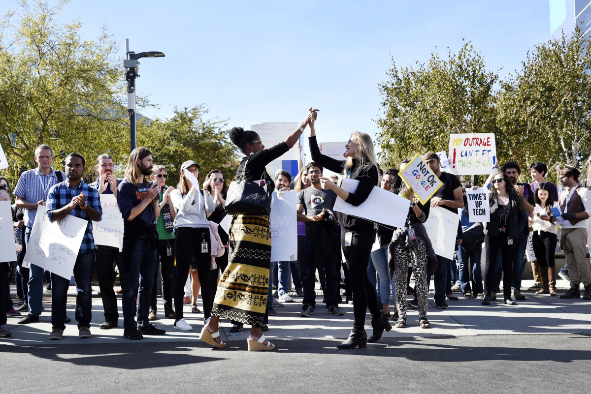 Two women high-five as Google employees hold signs during walkout in protest at Google's offices in Mountain View, Calif., on Nov. 1, 2018. MUST CREDIT: Bloomberg photo by Michael Short