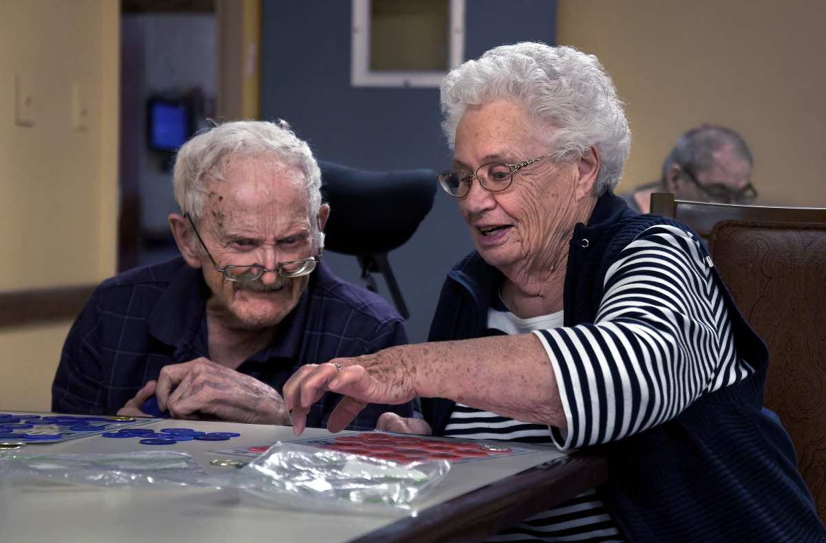Marlene helps Earl play bingo at Emerald Nursing & Rehab, his new care home. She now faces long trips to see her husband. MUST CREDIT: Washington Post photo by Michael S. Williamson