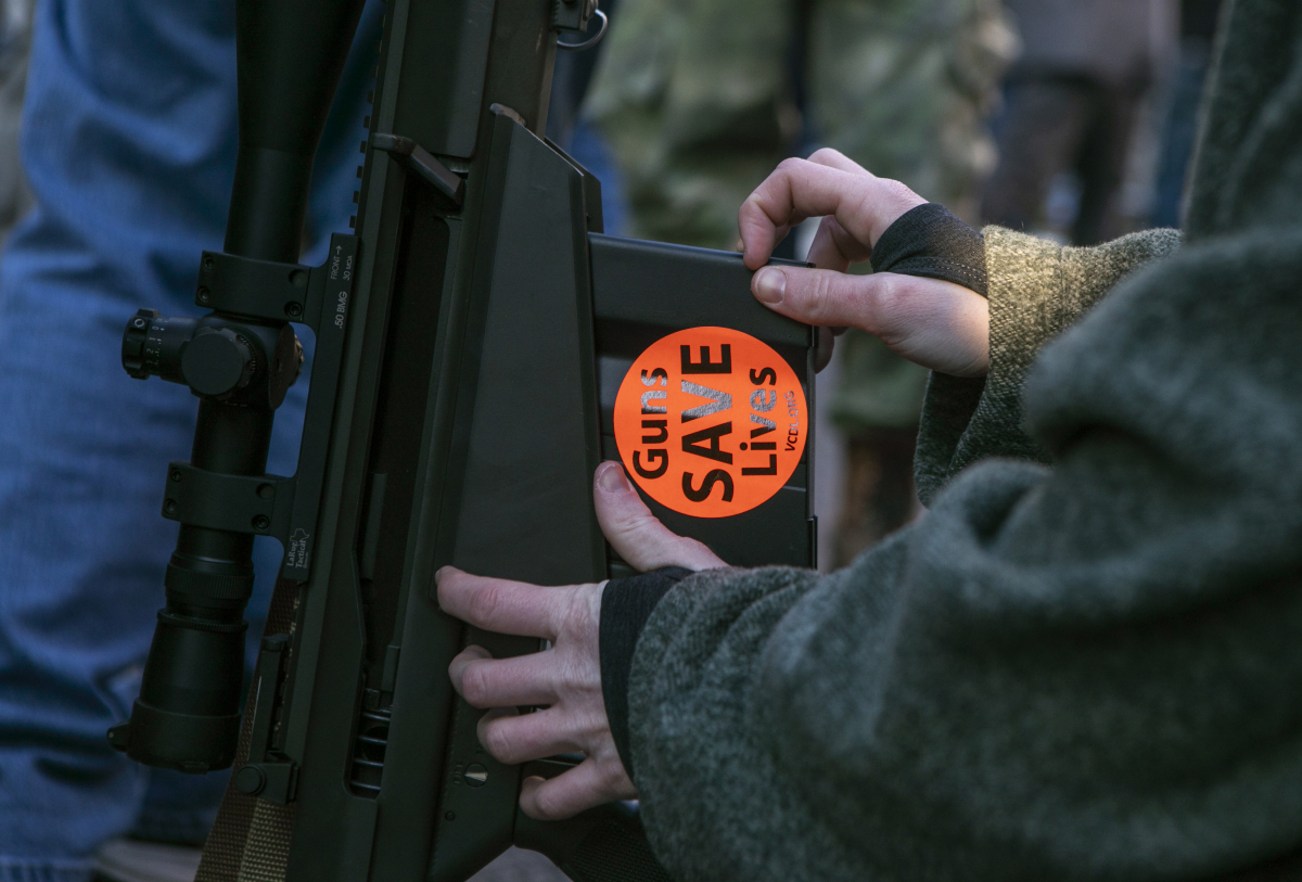 Anna-Marie Lewis puts a "Guns Save Lives" sticker on her husband's rifle during the gun advocates rally in Richmond, Virginia, on Jan. 20, 2020. MUST CREDIT: Photo for The Washington Post by Julia Rendleman
