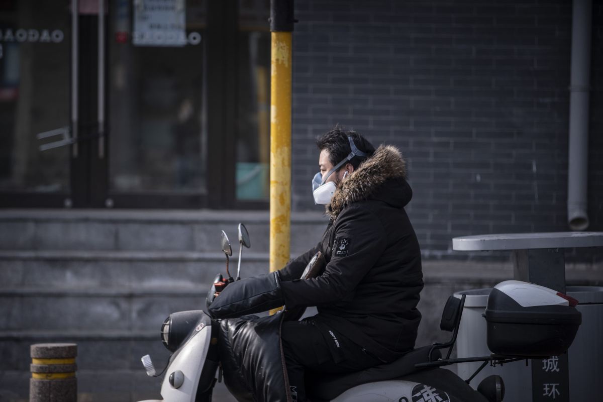 A motorcyclist wearing protective gear rides along a street in Beijing on March 18, 2020. MUST CREDIT: Bloomberg photo by Qilai Shen.
