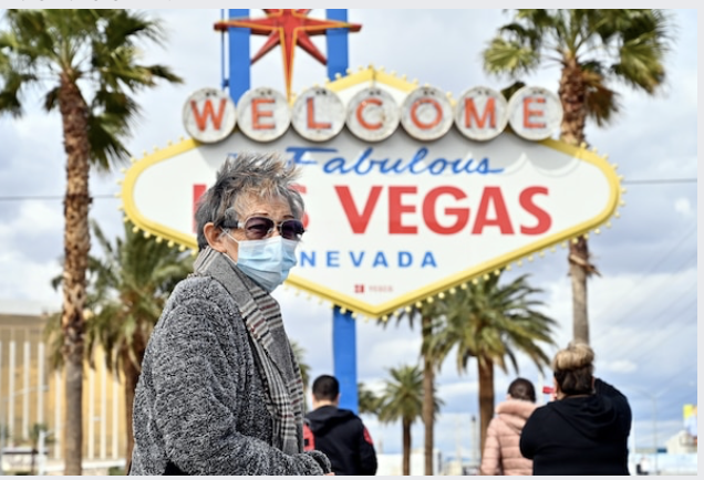 Bertha Lopez of Mexico wears a face mask as she visits the "Welcome to Las Vegas" sign Thursday. MUST CREDIT: Photo by David Becker for The Washington Post Photo by: David Becker — For The Washington Post Location: Las Vegas United States