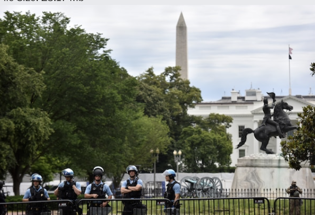 Authorities stand guard behind a large fence as dozens of protesters rally outside of Lafayete Square in Washington, D.C., on Tuesday. MUST CREDIT: Washington Post photo by Marvin Joseph