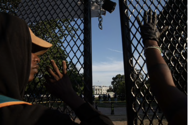 Protesters look through a fence from the White House's north side on Tuesday. MUST CREDIT: Photo by Evelyn Hockstein for The Washington Post Photo by: Evelyn Hockstein — For The Washington Post Location: Washington United States