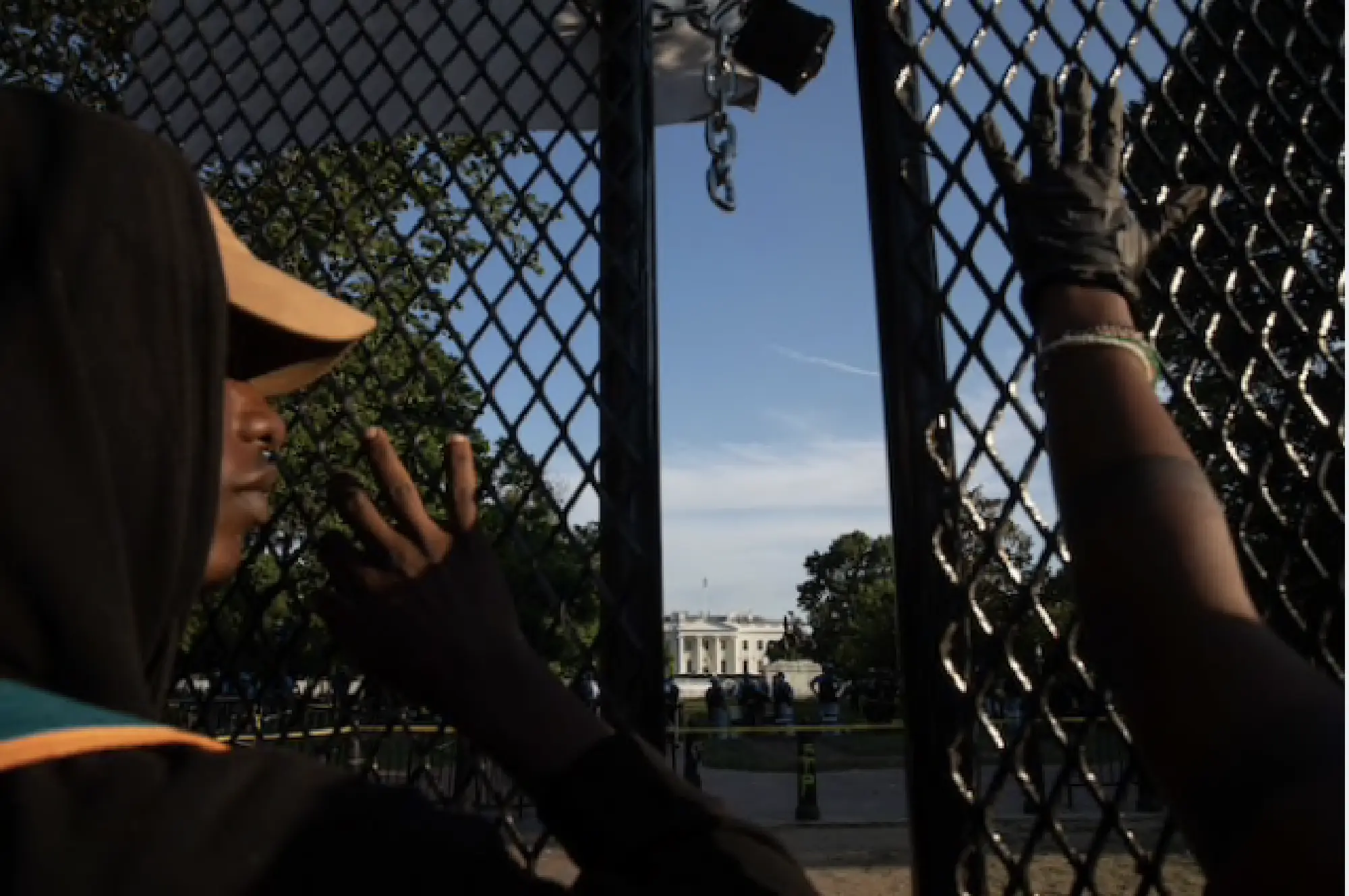 Protesters look through a fence from the White House's north side on Tuesday. MUST CREDIT: Photo by Evelyn Hockstein for The Washington Post Photo by: Evelyn Hockstein — For The Washington Post Location: Washington United States