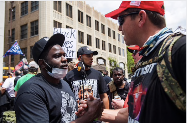 Dennis Johns of Topeka, Kansas, shakes hands with Nick Palmer of Oklahoma after a cordial discussion of their opposing views, amid tense confrontations outside Tulsa's BOK Center on Saturday. MUST CREDIT: Photo by Amanda Voisard for The Washington Post