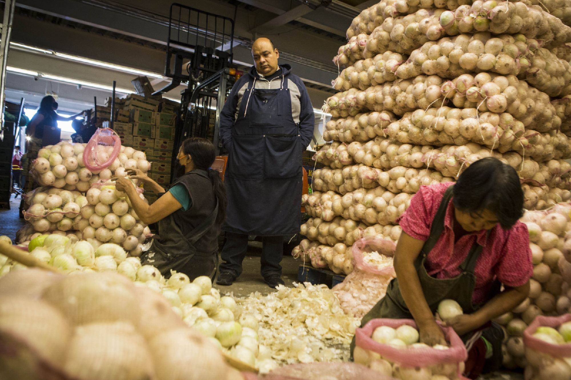 Omar Martinez watches as employees bag onions in his family's stall at the Central de Abastos in Mexico City on June 12, 2020. MUST CREDIT: Photo for The Washington Post by Jane Hahn