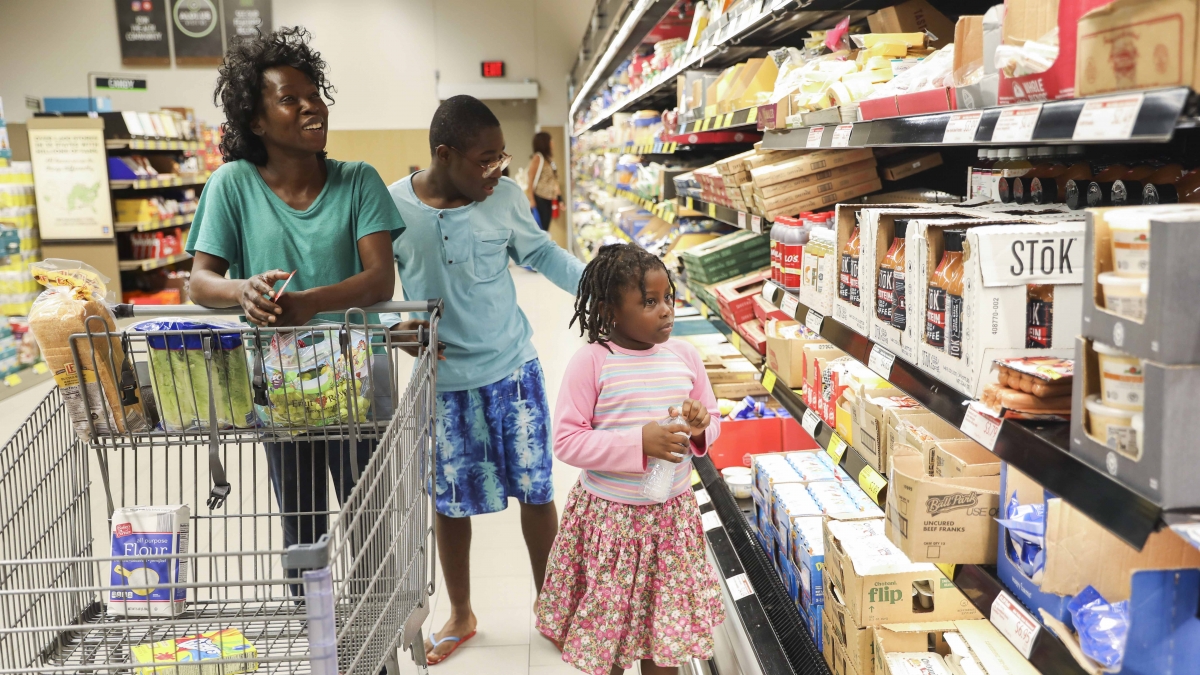 Sergine, Jayden and Phoenix go grocery shopping on June 19. Sergine said she's working on getting a license to open her own housecleaning business. Her husband, Dave, is continuing on at the construction job he started in May. MUST CREDIT: Photo by Eve Edelheit for The Washington Post.