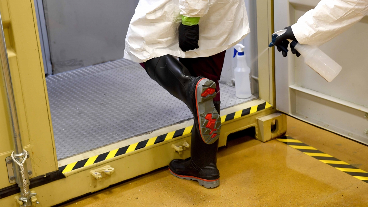 Technician Courtney Walton's boots are sprayed as he steps into an area where masks are cleaned. MUST CREDIT: Washington Post photo by Katherine Frey.