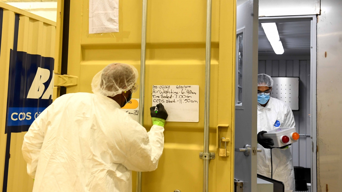 Decontamination Technician Troy Hubbard writes on a whiteboard that because humidity levels were high, the masks will take longer to clean after Courtney Walton took contamination meter readings on masks. MUST CREDIT: Washington Post photo by Katherine Frey.