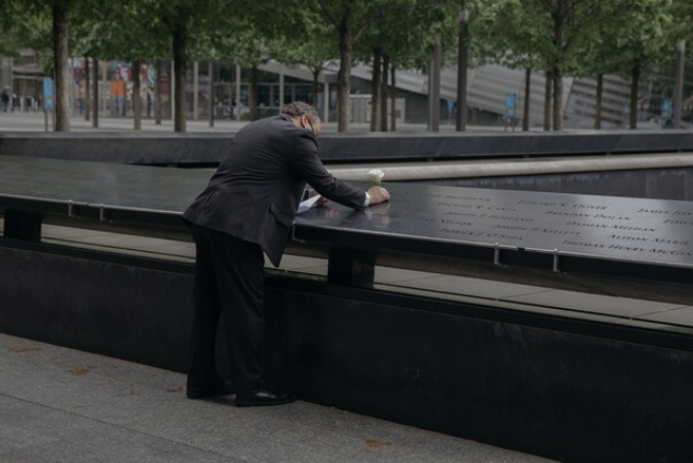 Eddie Mangual, a retired New York City police detective, places a white rose at the National September 11 Memorial Museum. MUST CREDIT: Photo by Celeste Sloman for The Washington Post
