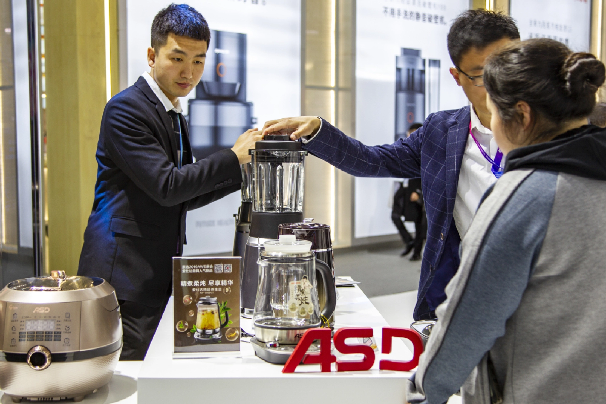 Salespeople inform a customer about multifunctional kettles that can boil tea, soup, porridge and medicinal preparations at an exhibition in Shanghai in 2019. [Photo provided to China Daily]