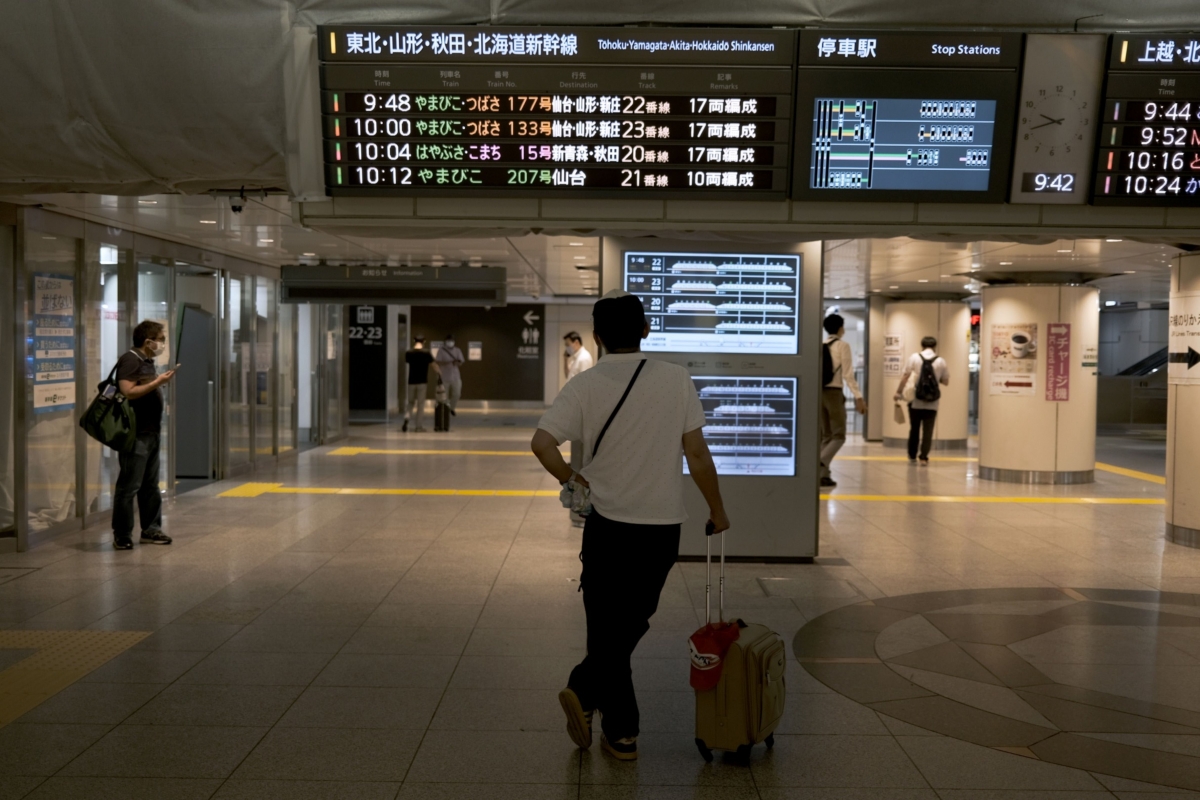 A passenger looks at a departure information board for East Japan Railway Co. (JR East) Shinkansen bullet trains at Tokyo Station on Aug. 7, 2020. MUST CREDIT: Bloomberg photo by Soichiro Koriyama.