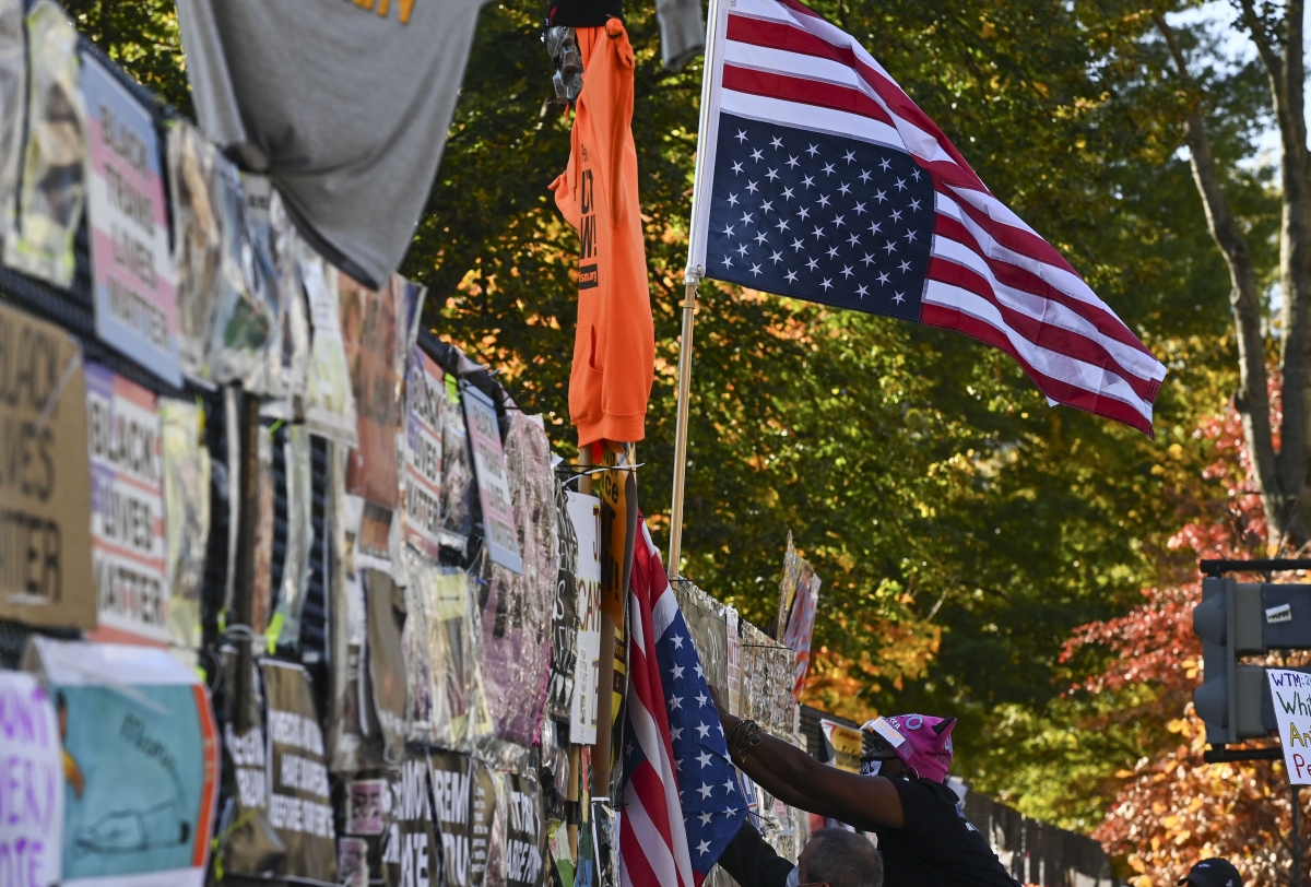 A woman hangs a U.S. flag upside down at Black Lives Matter Plaza as the nation waits for the results of the presidential election on Nov. 6, 2020 in Washington, D.C. MUST CREDIT: Washington Post photo by Ricky Carioti