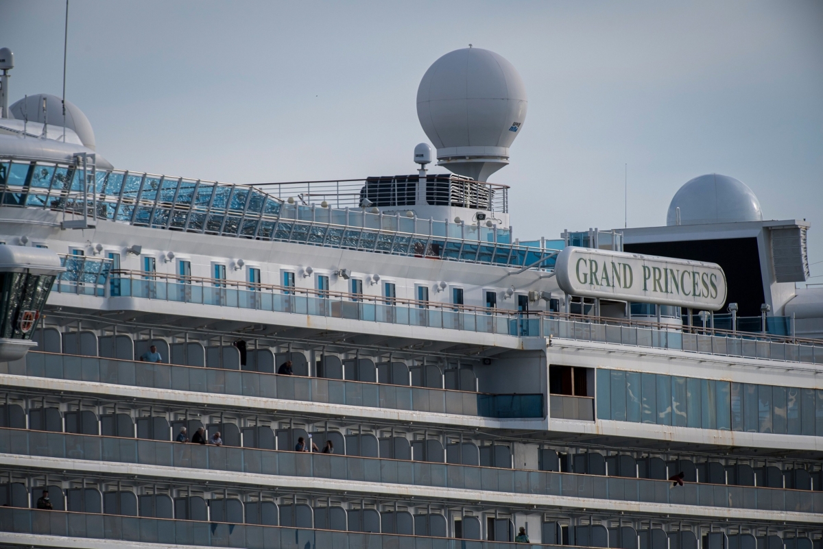 Passengers stand on their balconies of the Carnival Corp. Grand Princess cruise ship docked at the Port of Oakland in Oakland, California, U.S., on Monday, March 9, 2020. The cruise ship that spent days circling the waters off San Francisco with people sickened by the new coronavirus returned to land at an isolated dock, to begin the long process of offloading passengers into quarantine. Photographer: David Paul Morris/Bloomberg