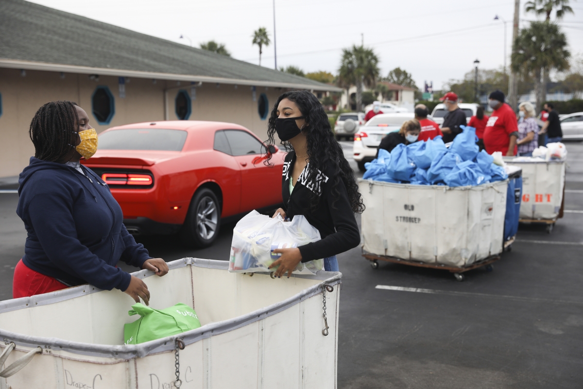 Volunteers Kyla Smith, left, and Kendra Rodriguez wait to hand out food at the Seasons Florida Resort in Kissimmee. MUST CREDIT: Photo by Eve Edelheit for The Washington Post.