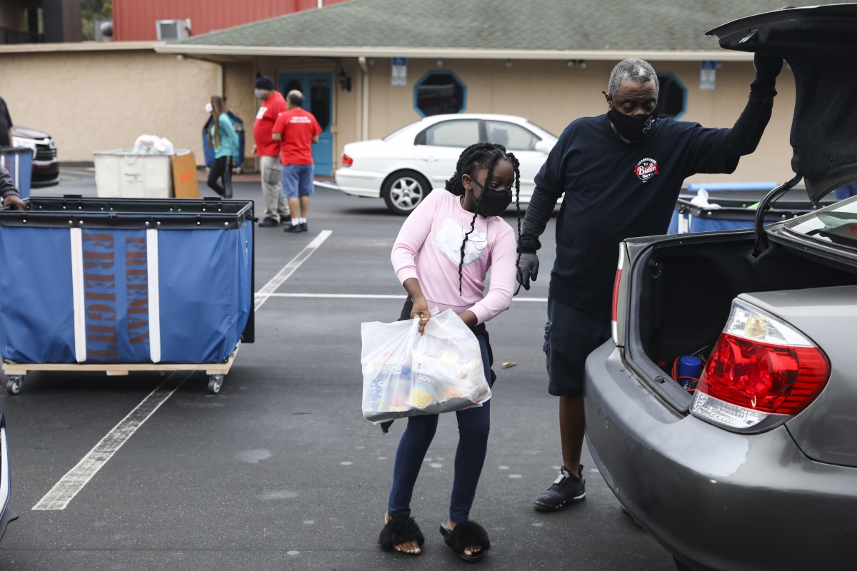 Fernaly Nazaire, 7, brings donated food to cars at the Seasons Florida Resort in Kissimmee. MUST CREDIT: Photo by Eve Edelheit for The Washington Post.