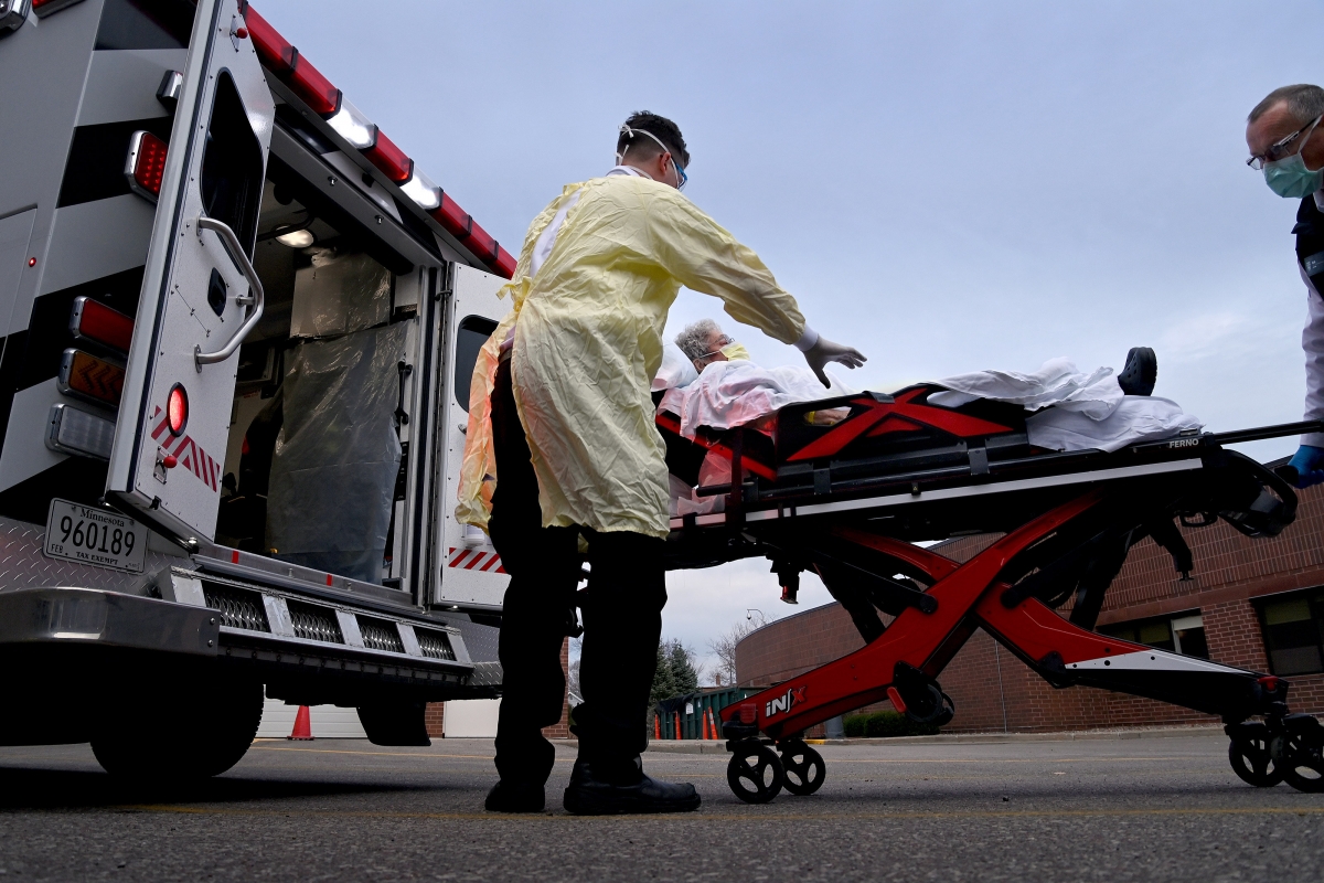 Mayo Clinic paramedic Adam Glass, a paramedic with the Mayo Clinic, helps load covid-19 patient Rita Huebner into an ambulance in Eau Claire, Wis., on Nov. 18, 2020. MUST CREDIT: Washington Post photo by Michael S. Williamson.