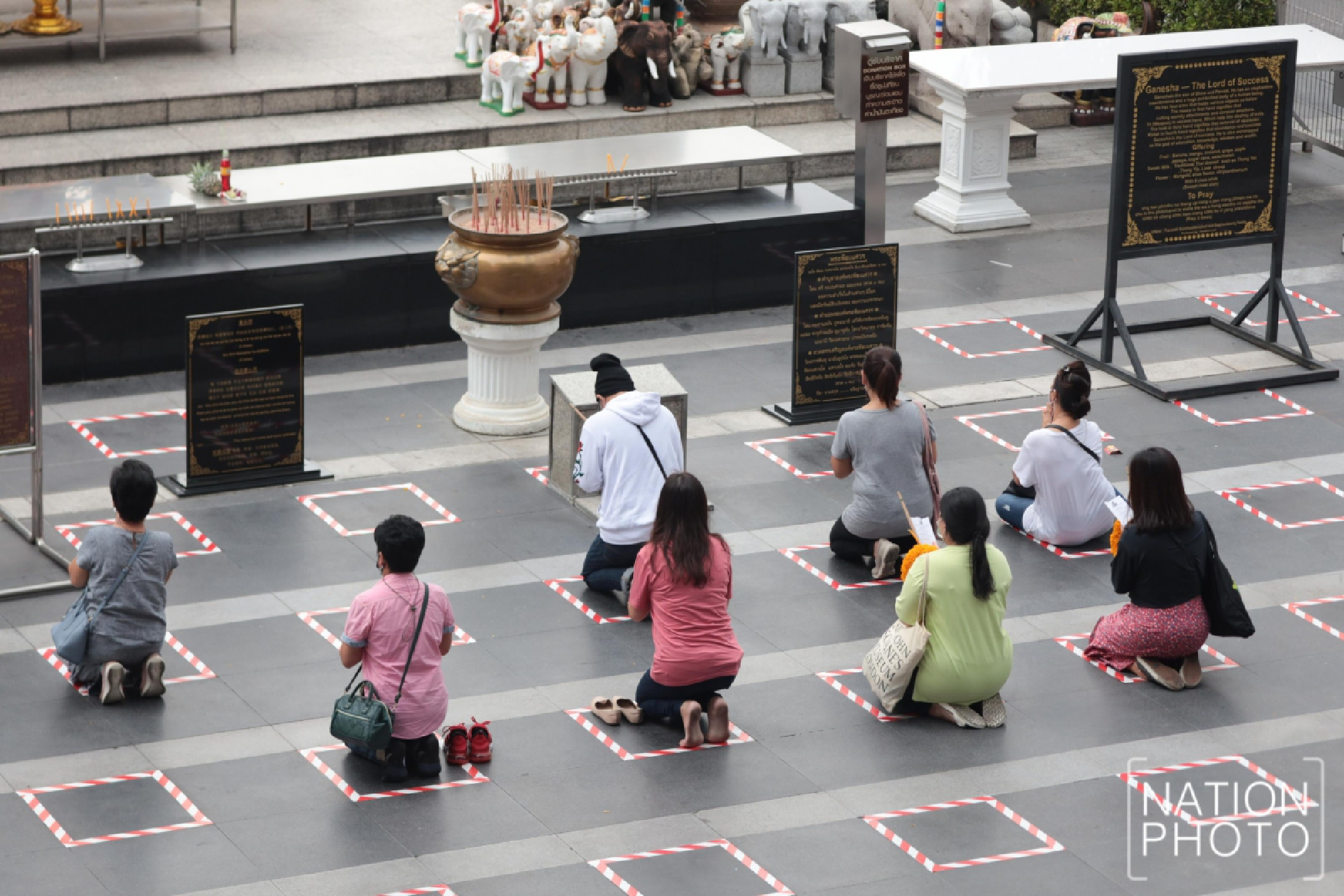 People who pay respects at the Hindu shrine outside Isetan department store in Bangkok have to stay in the marked space as a precaution against virus infection.
