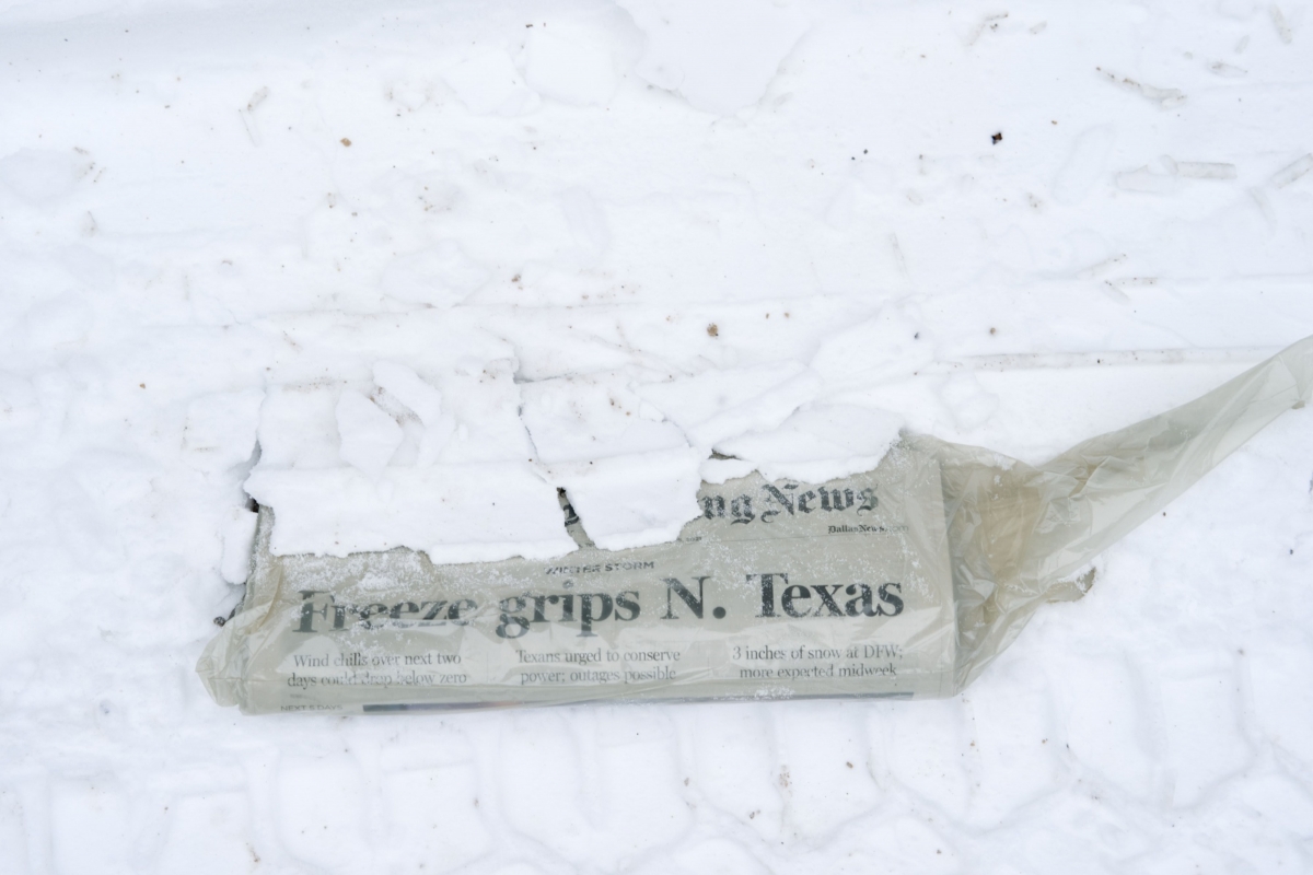 A Dallas Morning News newspaper half-covered in snow on Feb. 16, 2021, in McKinney, Texas, about 30 miles north of Dallas. MUST CREDIT: Bloomberg photo by Cooper Neill